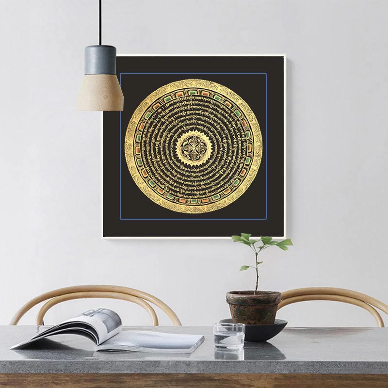 Black-framed Tibetan six-syllable mantra thangka with thin blue border and gold scripture patterns hanging above minimalist dining table