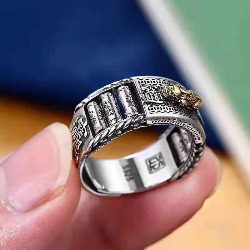 Gold-plated Pixiu prayer wheel ring held between fingers showing inner S925 hallmark and rotating carved tube elements