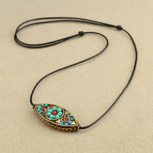 Tibetan turquoise marquise pendant necklace with ethnic red enamel inlay and black waxed cord, flat lay top view