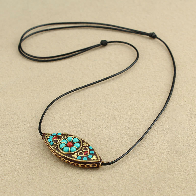 Tibetan turquoise marquise pendant necklace with ethnic red enamel inlay and black waxed cord, flat lay top view