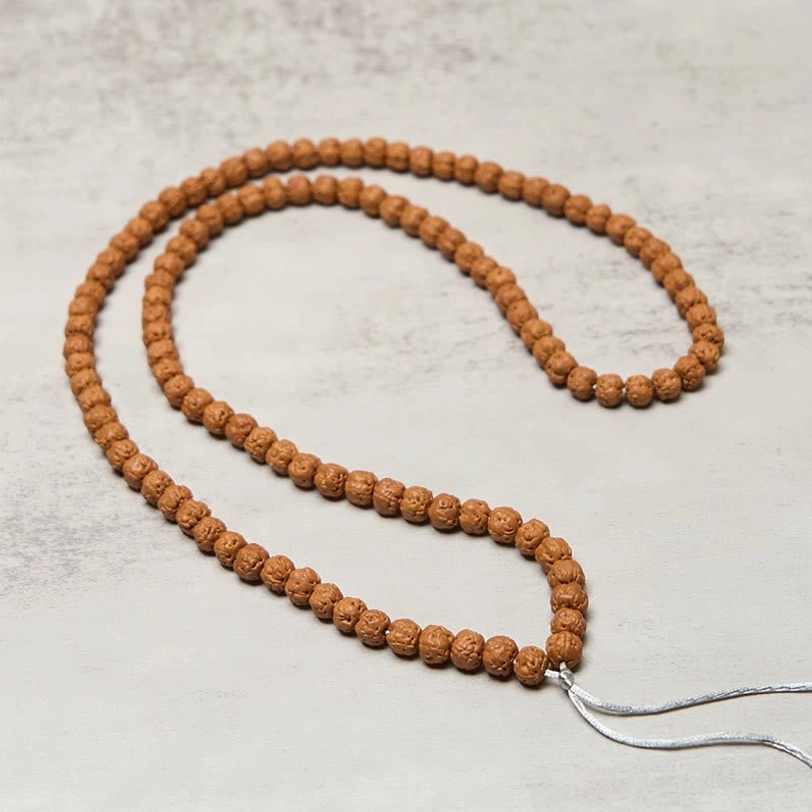 108 bodhi bead mala laid out in two loose loops showing full strand length and silver end tassels
