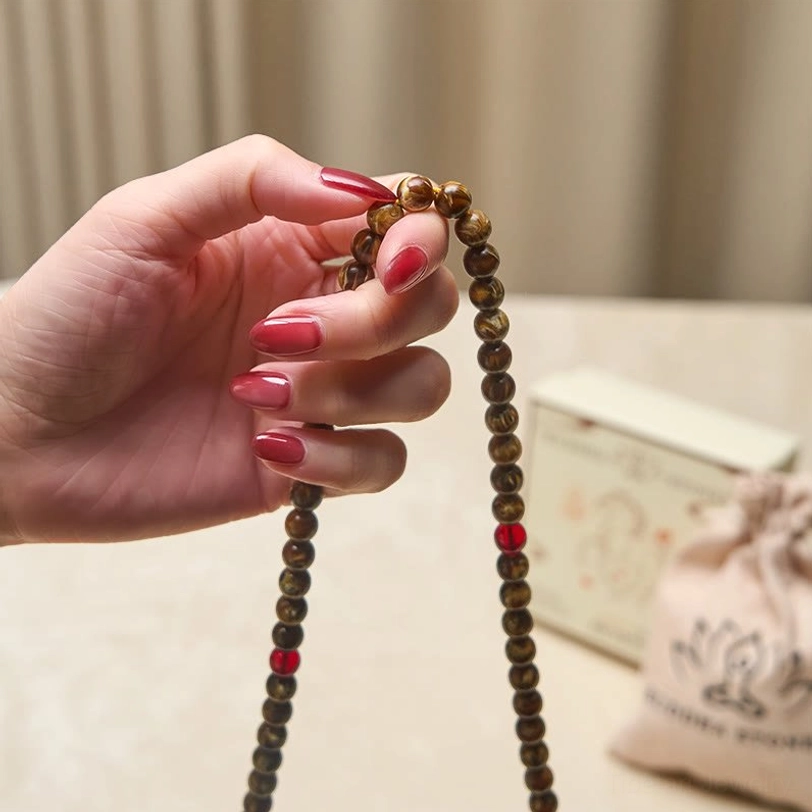 Hand holding amber mala beads showing tactile texture and warm honey glow of faux amber material