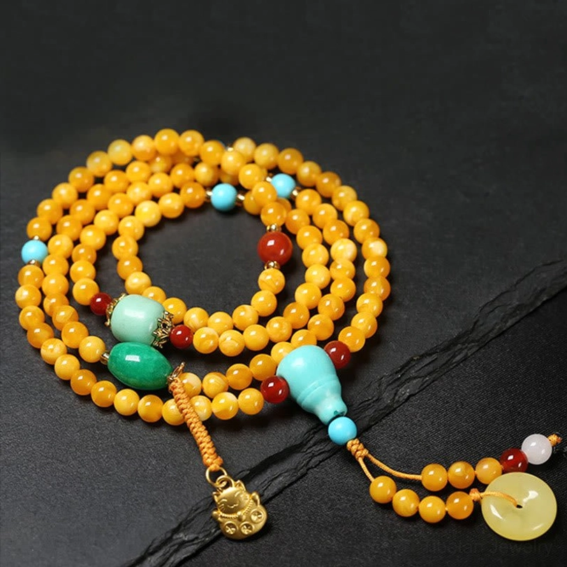 Tibetan amber mala prayer beads with green jade turquoise red agate gold chain and lucky charm accent flat lay