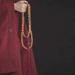 108 bodhi seed mala beads bracelet with red tassel worn on wrist, showing natural brown beads and traditional styling