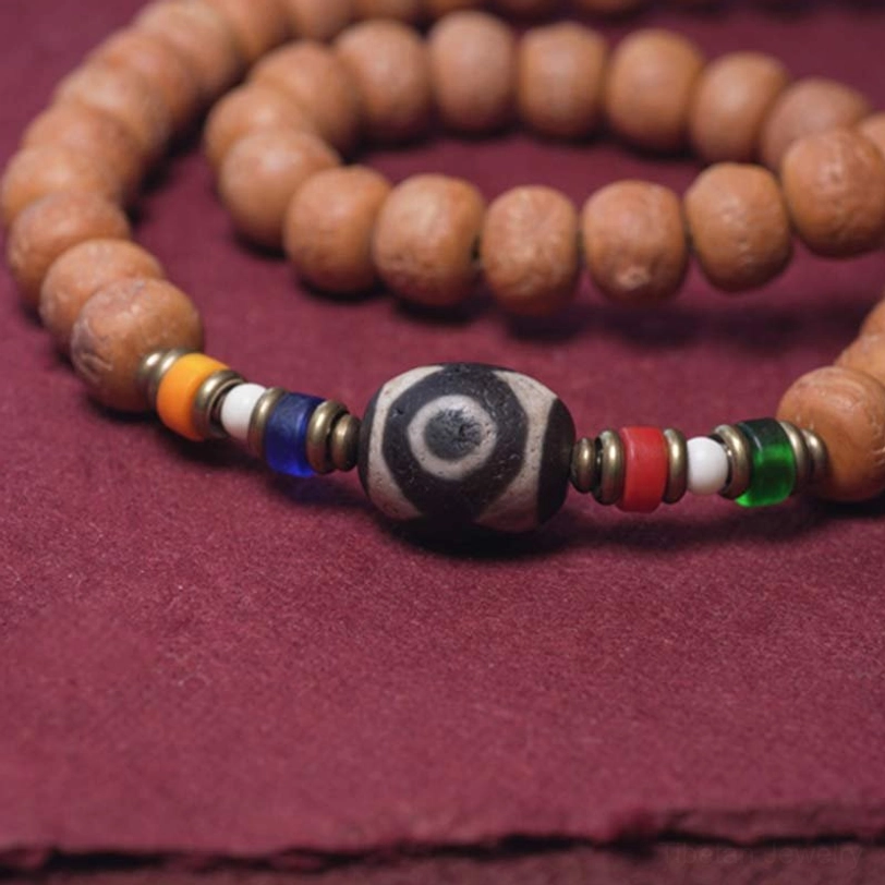 108 mala bead strand flat lay showing dzi bead accent, colorful spacer beads, and traditional red tassel
