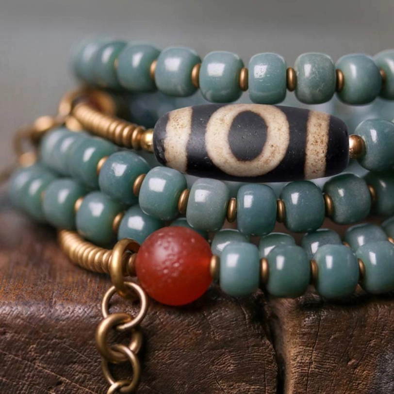 Macro Close-Up Detail of Mala Bracelet Showing Striped Dzi Bead and Teal Bodhi Seeds with Brass Connector