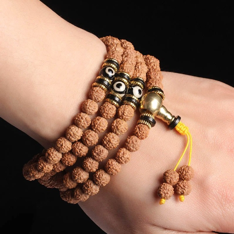 Worn 108 mala bracelet on wrist with brown rudraksha beads, metal accents, and yellow tassel with rudraksha pendants