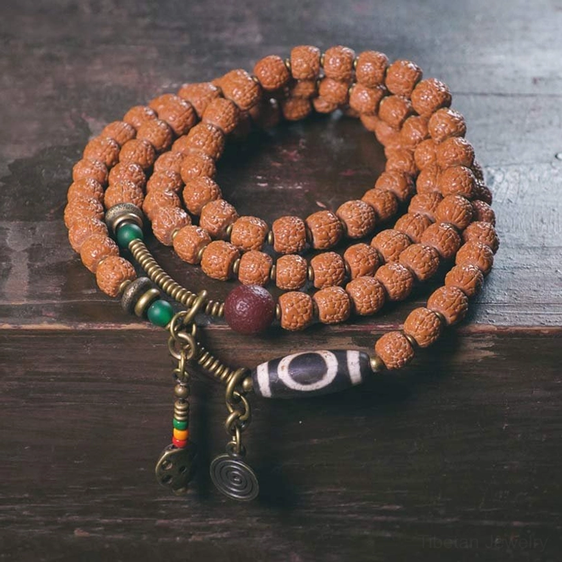 108 Rudraksha Mala Bracelet with Nine-Eye Dzi Bead displayed on dark wooden surface, showing complete design with tassel and multi-loop arrangement