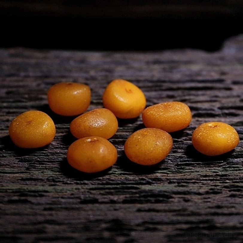 108 Tibetan prayer beads flat lay showing light yellow round beads with red and brown spacer beads on wood