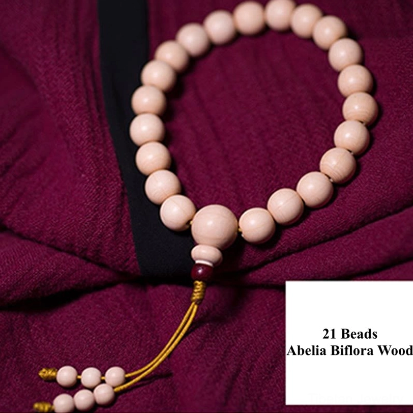 Complete flat lay of Abelia Biflora wood 21-bead wrist mala with labeled bead count, cream-colored wooden beads, and traditional yellow tassel decoration