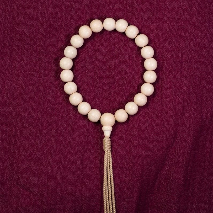 Natural Abelia Biflora wood wrist mala in both 10mm and 12mm bead size variations showing cream-colored beads with yellow tassel accent