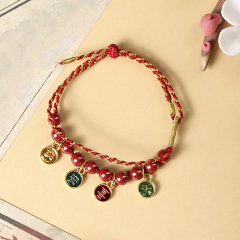 Adjustable red string cinnabar bracelet on vintage paper background with flower props, showing traditional spiritual aesthetic