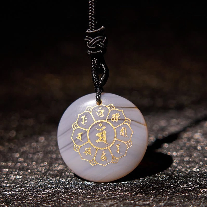 Agate tibetan mantra pendant close-up showing detailed Sanskrit engraving and polished stone