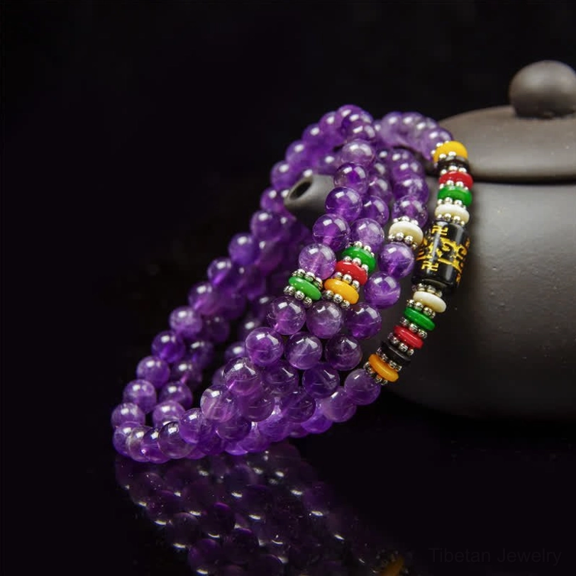 Purple amethyst prayer mala with mantra beads and mirror reflection on dark background