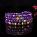 Amethyst 108-bead mala bracelet with colorful mantra spacers displayed on dark background with mirror reflection