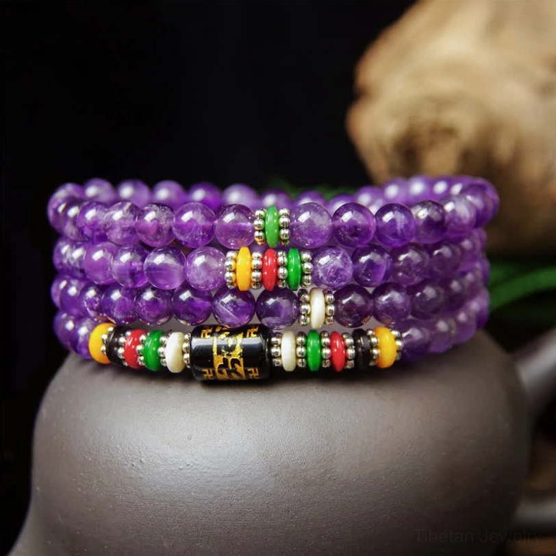 Amethyst 108-bead mala necklace placed on purple clay teapot showing bead details and colorful spacers