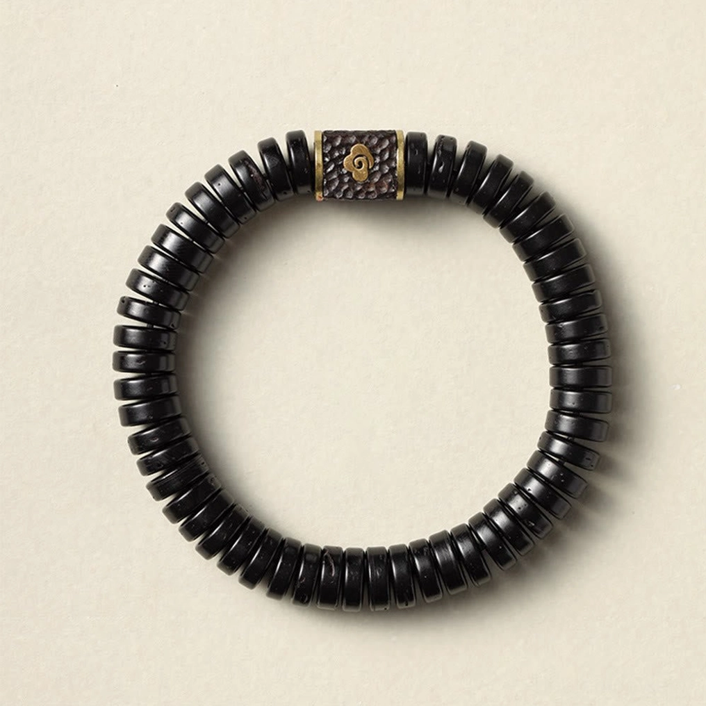 Black coconut shell auspicious bracelet top-down view showing polished disc beads and central metal charm