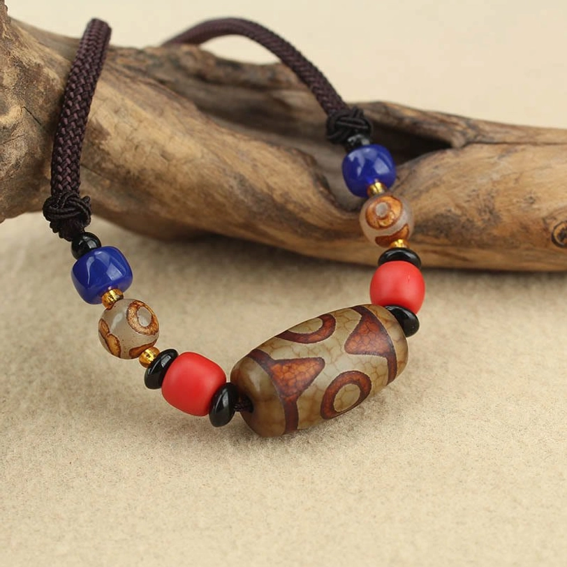 Authentic tibetan dzi bead necklace showing natural agate texture and hand-painted eye patterns with adjustable cord mechanism