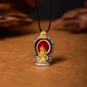 Tibetan Avalokitesvara copper dzi pendant necklace front view with gilt Buddha carving on wooden surface