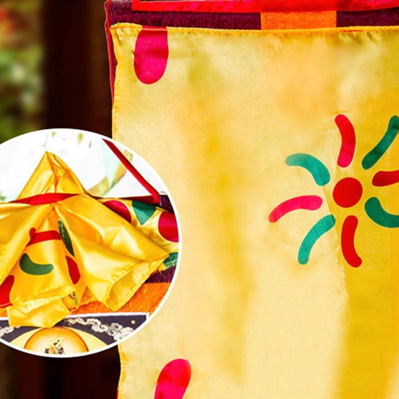 Hand-painted Tibetan thangka decoration close-up showing yellow satin fabric and colorful religious artwork detail magnified view