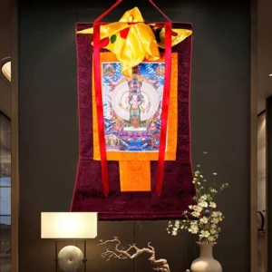 Tibetan Avalokitesvara thangka wall art displayed in modern home interior showing colorful religious deity painting with maroon fabric frame
