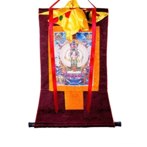 Thousand-armed Avalokitesvara thangka framed scroll with dark red brocade border, yellow satin top cover and red hanging ribbons on white background
