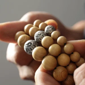 Wooden bagua bracelet held in hand showing multiple silver-engraved spacer beads - close-up detail shot
