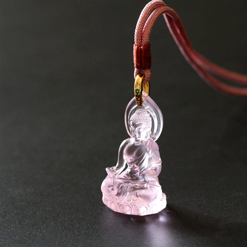 Medicine Buddha Bhaisajyaguru pendant showing detailed Buddha deity figure with ritual bowl and lotus throne on translucent Liuli crystal