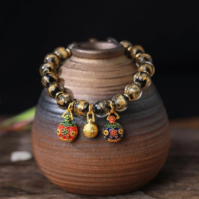 Black gold tone liuli glass bead bracelet with enamel swallowing beast and gold bell charm