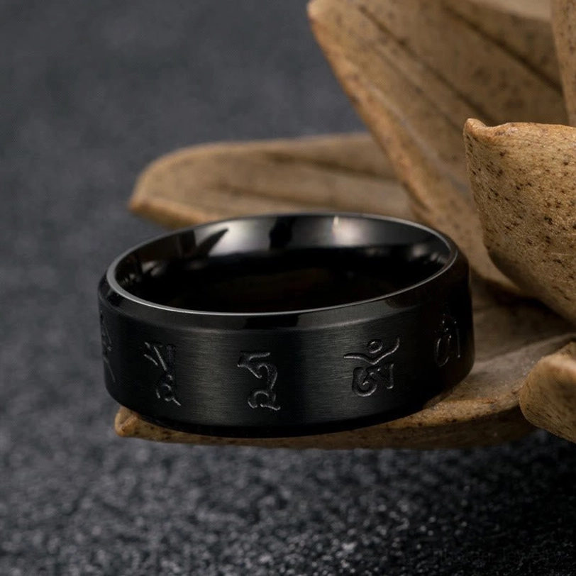 Black Jambhala mantra titanium steel ring top-down close-up with wooden lotus ornament, showing engraved Buddhist mantras on band