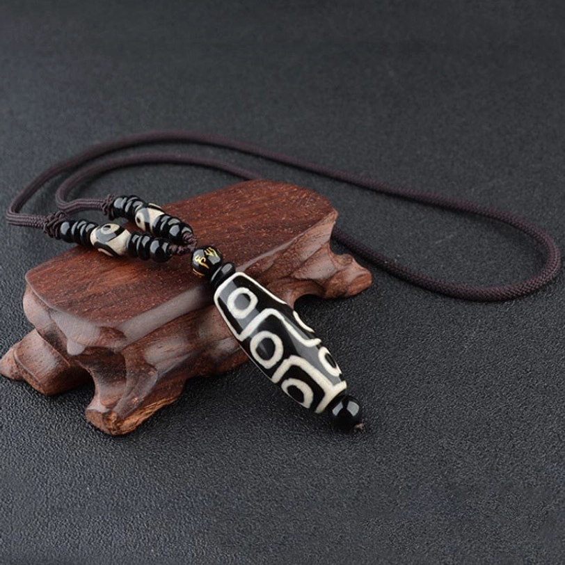 Classic black nine-eye Dzi bead necklace with hand-painted agate pendant on wooden stand, featuring traditional Tibetan spiritual jewelry design