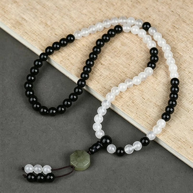 Black Obsidian Bagua protection bracelet with jade trigram charm displayed on wooden surface