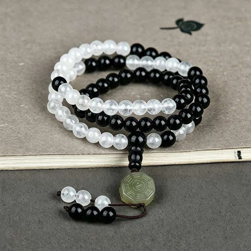 Stacked Black Obsidian Bagua bracelets with tassel decoration on dark background