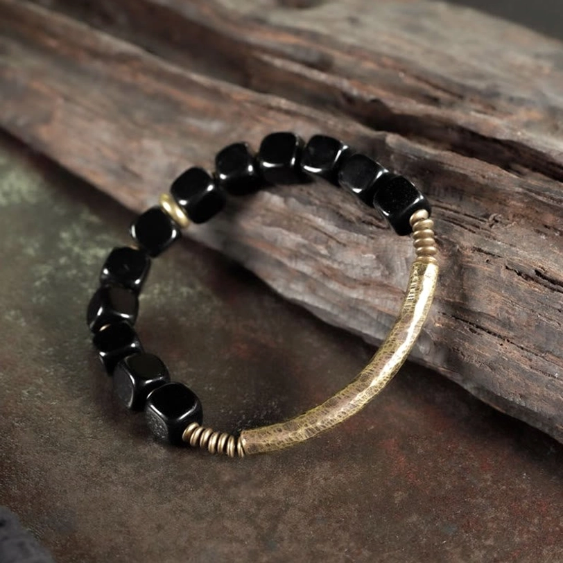 Black obsidian couple bracelet displayed on weathered wood and dark background with rustic aesthetic, natural scene
