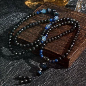 Loose Black Obsidian mala beads and strands arranged on wooden coaster, displaying individual bead quality and blue decorative stone details