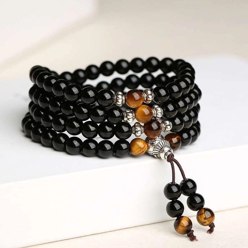Black obsidian tiger eye 108 bead mala bracelet front flat lay, white background showing complete bracelet with guru bead and tassel