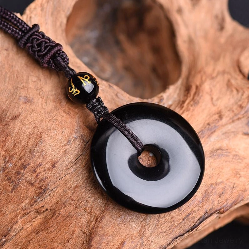 Black obsidian peace buckle necklace side view showing braided cord and polished stone surface