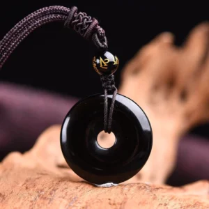 Solid black obsidian peace buckle necklace front view with polished round pendant and Sanskrit bead detail