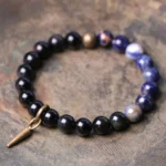 Black Obsidian and blue Sodalite couple bracelet with copper spike clasp on wooden background - natural stone healing bracelet