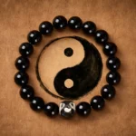 Black Onyx Yin Yang balance bracelet with glossy round beads and metallic Yin Yang charm on leather backdrop