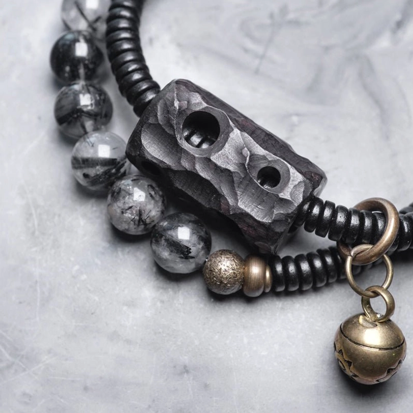 Close-up detail of black rutilated quartz beads with brass metal spacers and ebony wood charm
