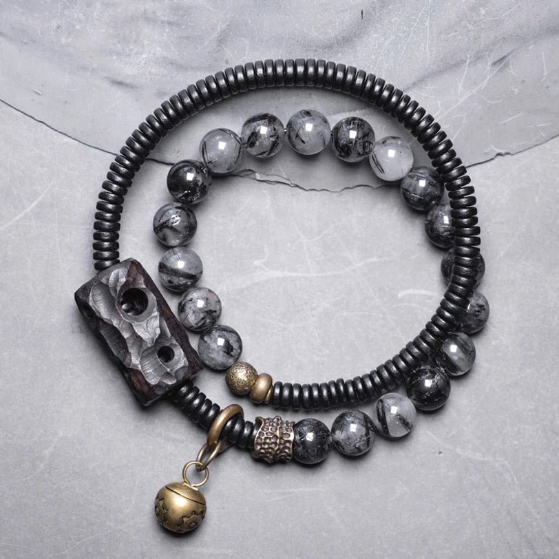 Black rutilated quartz ebony wood copper couple bracelet set flat lay with brass bell charm