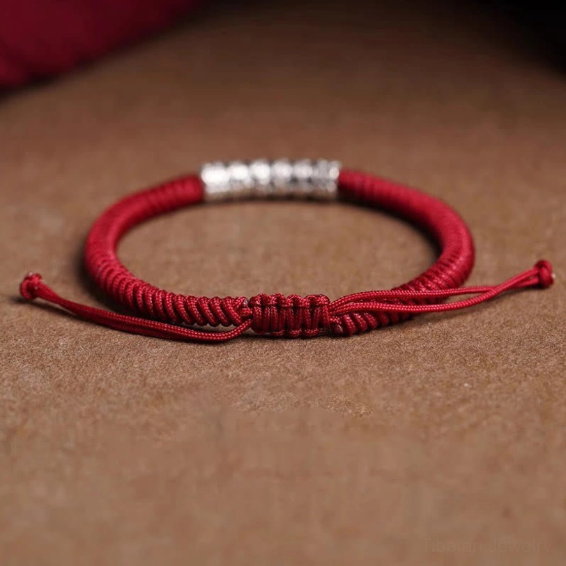 Black Tibetan Om Mani Padme Hum protection rope bracelet with sterling silver engraved charm, flat lay product shot