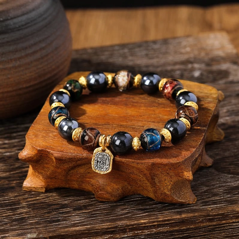 Mixed blue-brown liuli glass wealth bracelet overhead view with multicolored beads and engraved square charm