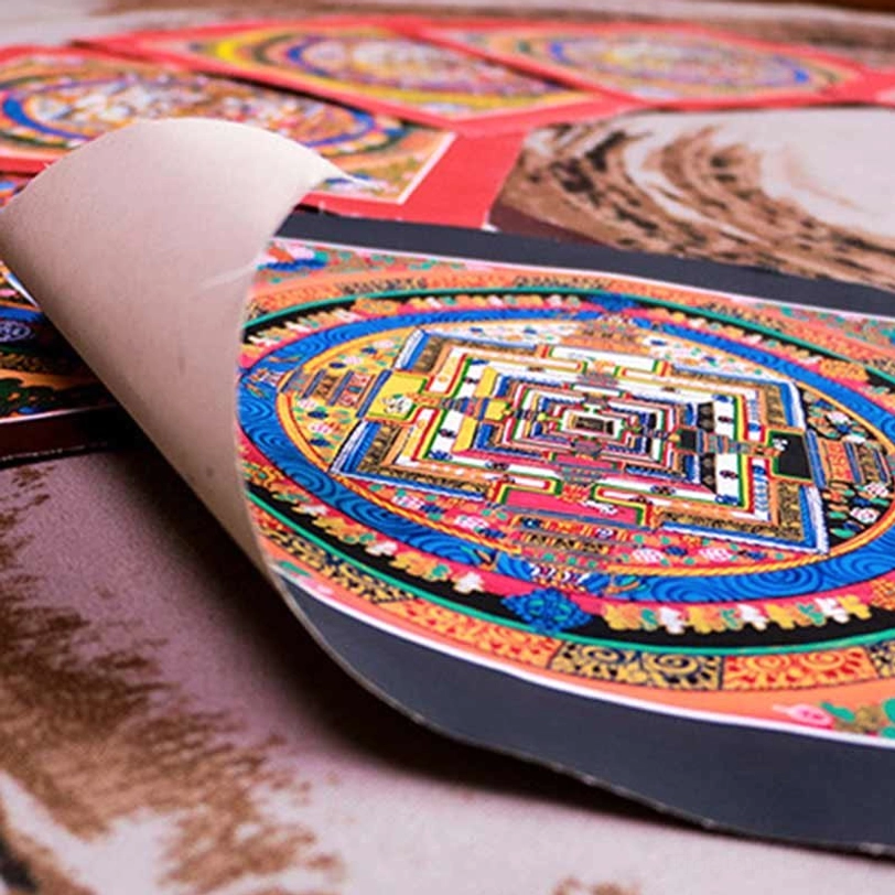 Unrolled Tibetan mandala thangka featuring rich blue and gold circular patterns with rolled paper edge