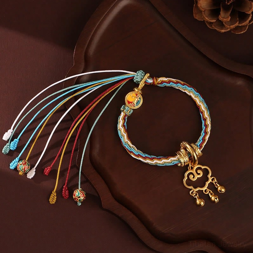 Blue and white tibetan healing bracelet with multicolor enamel charms and cloud lock pendant on dark tray with natural decor