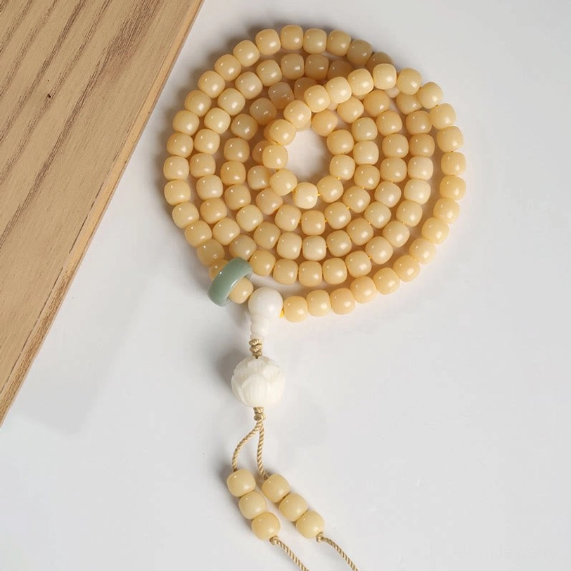 Circular arrangement of tibetan bodhi seed beads with lotus tassel pendant on wooden surface