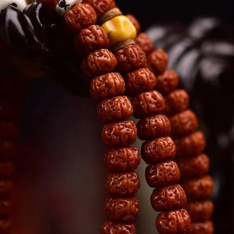 Bodhi seed strand close-up macro shot displaying compact disc-shaped reddish-brown beads with dense carved natural texture