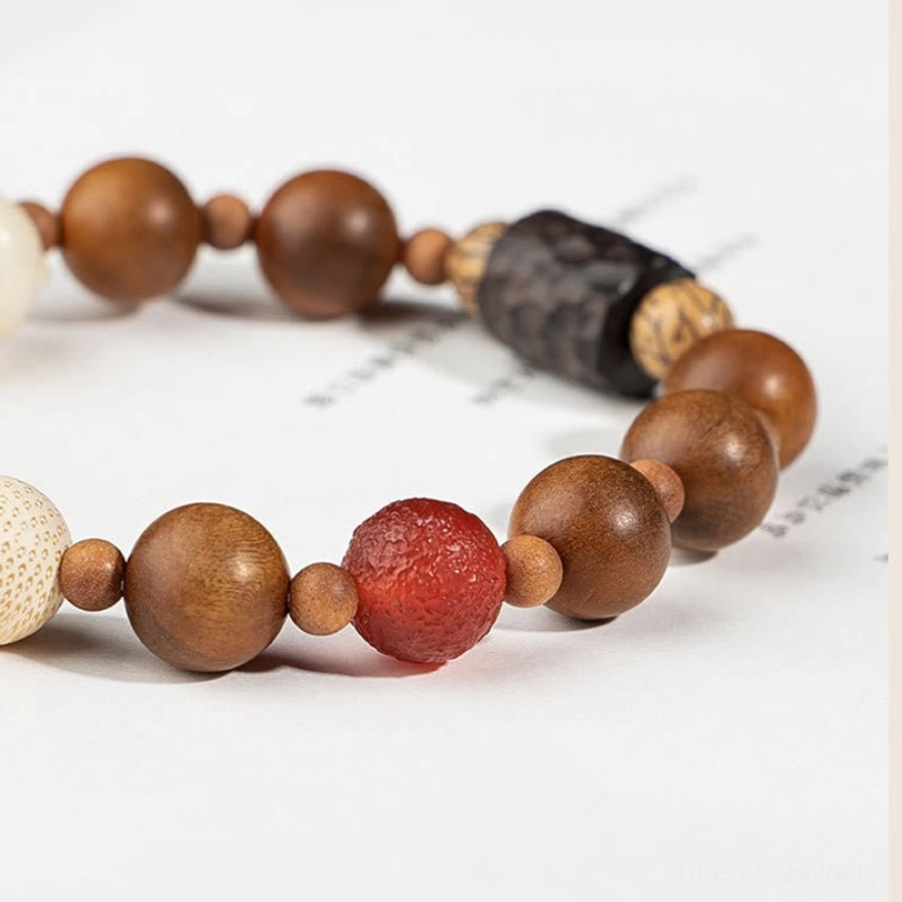 Wooden bodhi bead bracelet featuring large red agate bead and textured spacer beads, side flat lay on light background
