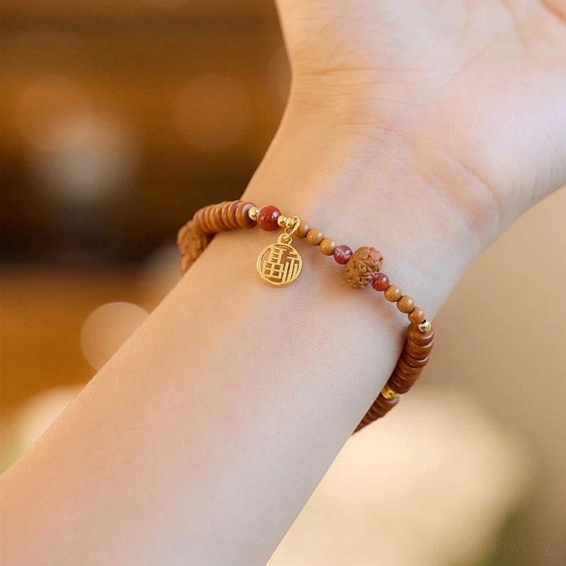 Bodhi seed bracelet worn on wrist side view, displaying gold Fu prosperity charm and red agate accents